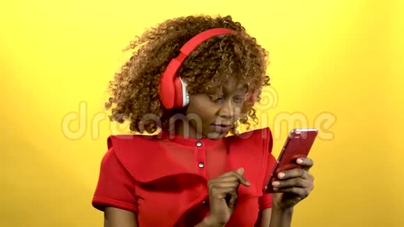 美国黑人女孩戴着耳机唱歌黄色背景视频的预览图