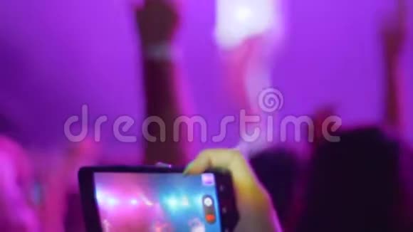 在灯光照明的背景下观众在夜间音乐会上通过电话进行现场直播视频的预览图