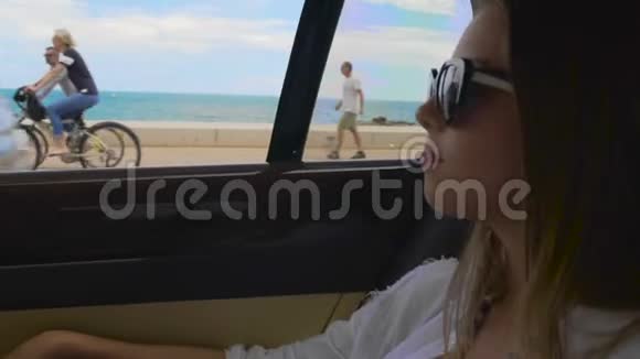 成功的女性骑在度假城市海滨的汽车后座视频的预览图