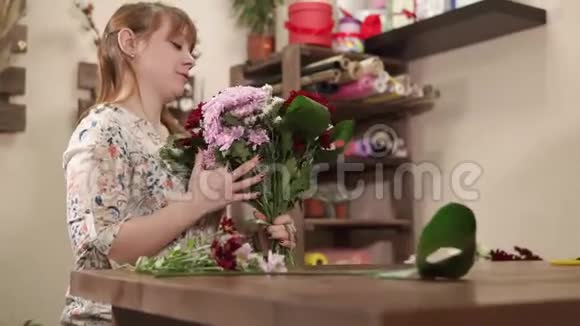 有礼貌的微笑女孩正在花店里收拾花束视频的预览图