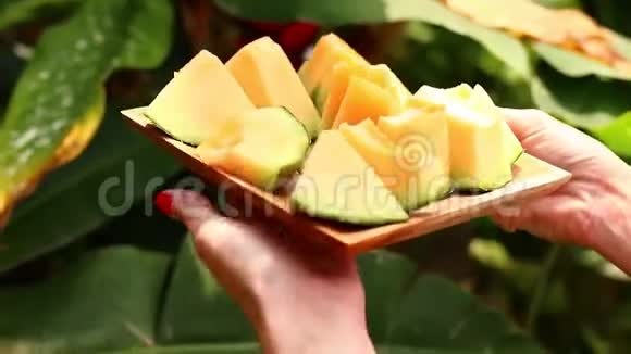 女人的手在木碗里拿着甜瓜热带背景视频的预览图