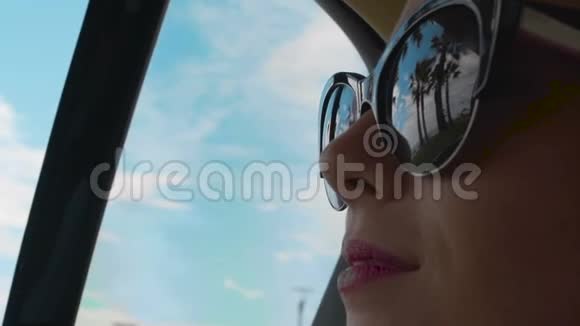 坐在汽车后座的女人戴着墨镜的手掌和海边倒影视频的预览图