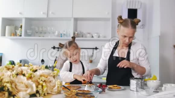 厨房里的妈妈和她的小女儿装饰早餐的甜点视频的预览图