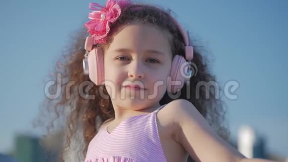 一个卷发可爱的孩子的肖像一个穿着粉色衣服穿着粉色花朵的白种人小女孩的夏天视频的预览图