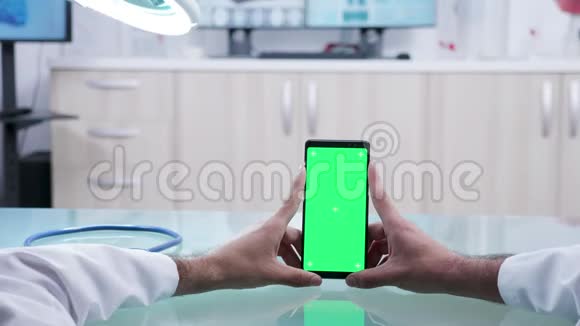 男医生手拿着绿色屏幕的手机视频的预览图
