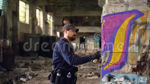 一位年轻的职业涂鸦画家正在废弃的建筑里工作他正在用喷雾漆画视频的预览图