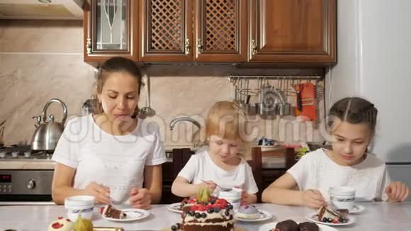 妈妈和两个女儿正在厨房里喝一杯带自制巧克力蛋糕的茶家里过生日视频的预览图