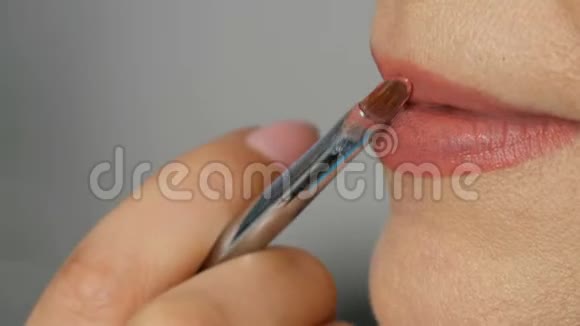 中年成年女性在美容院发型师用特殊的画笔用口红画嘴唇褪色视频的预览图