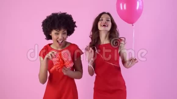 年轻女子工作室与穿着红色连衣裙带礼物气球的粉红女子隔绝视频的预览图
