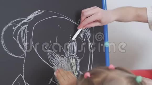 妈妈教小女孩用粉笔在黑板上画画视频的预览图