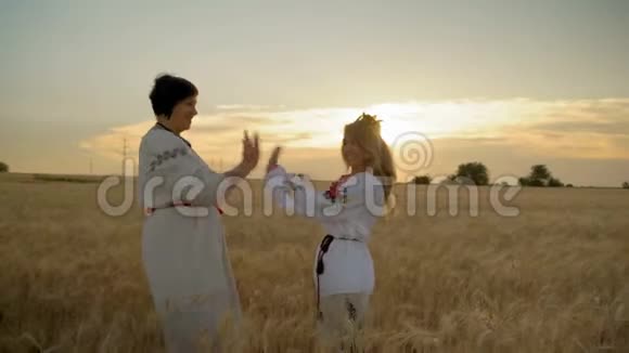 黎明时分两个快乐的女人在麦田上拍手视频的预览图