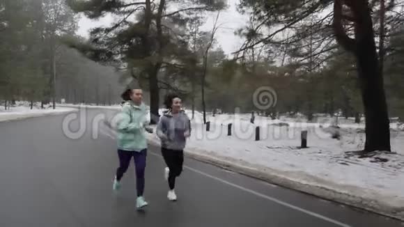 快乐的年长和年轻的高加索女人在冬天的雪地公园里奔跑交谈和微笑前面跟射弹视频的预览图