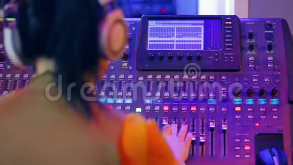 女士DJ耳机后混合控制台工作在彩色照明视频的预览图