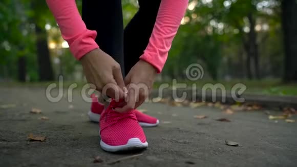 在日落时分女人系鞋带穿过一个秋天的公园视频的预览图