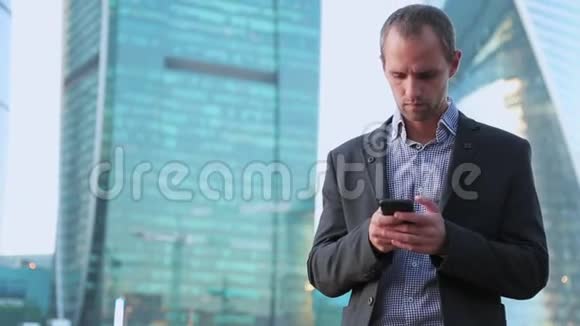 英俊的成年男子站在城市街道上发短信的肖像商人在读短信视频的预览图