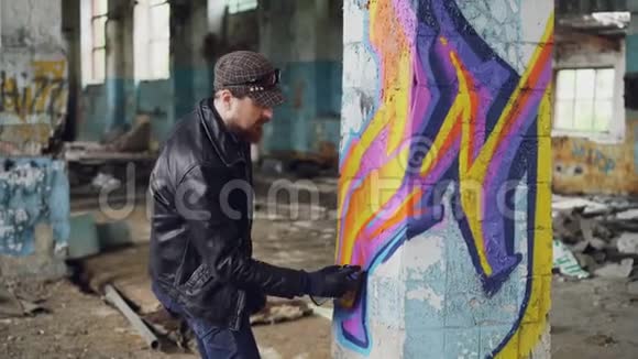 专业的涂鸦画家用喷漆在废弃建筑内的大柱子上创造抽象的形象视频的预览图