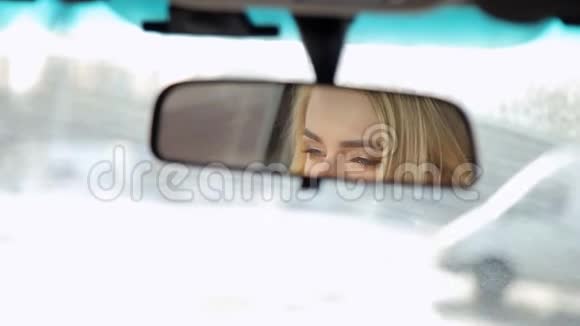 一个微笑的女孩在汽车的镜子里的倒影视频的预览图