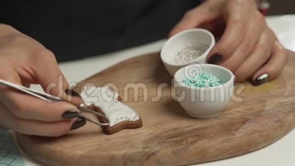 一个年轻的女孩在圣诞节的冬天晚上装饰姜饼女人在蜂蜜姜饼屋里引火烧身木制视频的预览图