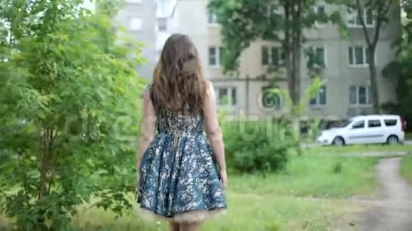 年轻的黑发女人走在树附近的街道上头发随风飘扬女孩转过身来视频的预览图
