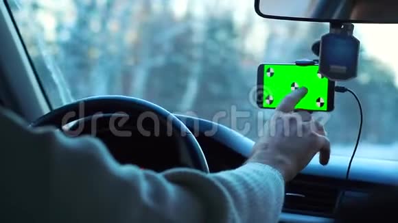 冬天开车的人智能手机有一个绿色的屏幕贴在挡风玻璃上它把手指按在挡风玻璃上视频的预览图