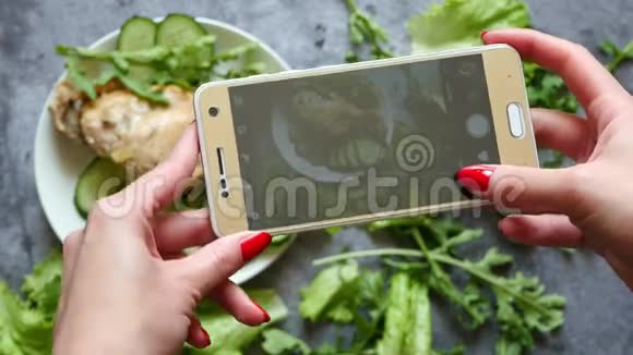 一位年轻女性在智能手机上为社交网络拍照她的食物从上面看视频的预览图
