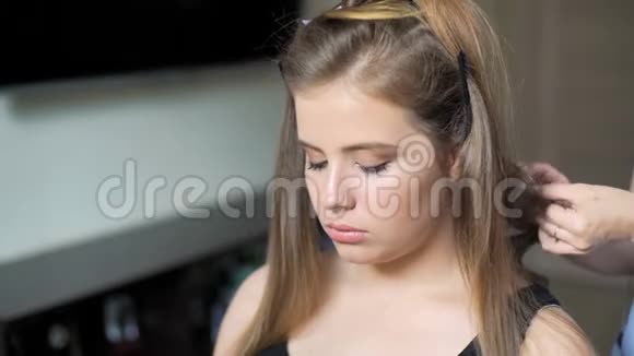 发型师为女孩创造一个发型使头发级联视频的预览图