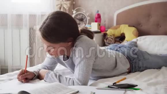 可爱的小女孩躺在床上做作业视频的预览图