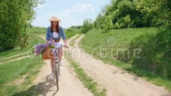 戴着帽子的可爱女孩骑着自行车在大自然中旅行视频的预览图