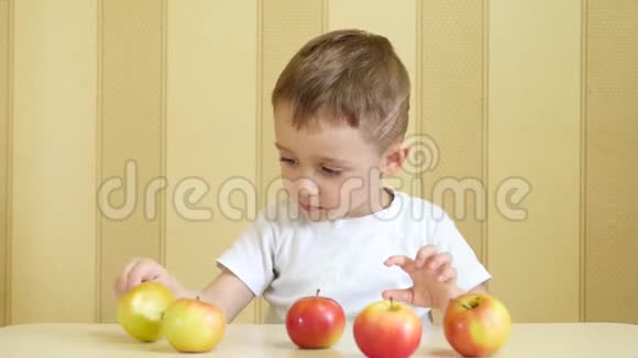 幼儿边吃边玩红苹果和绿苹果边坐在桌旁出示快乐的大拇指视频的预览图