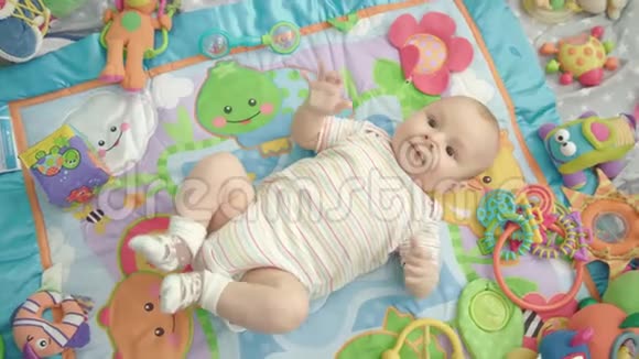 小宝宝躺在五颜六色的地毯上带着玩具婴儿男孩肖像视频的预览图