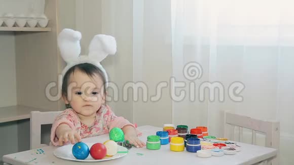 穿着兔子的女孩坐在一张白色的桌子旁复活节假日视频的预览图