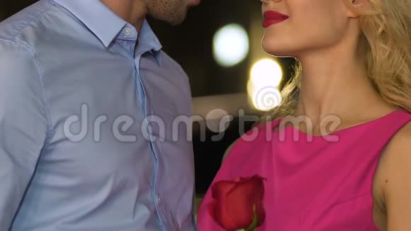 迷人的男人亲吻金发女人捧着红玫瑰甜蜜浪漫的约会视频的预览图