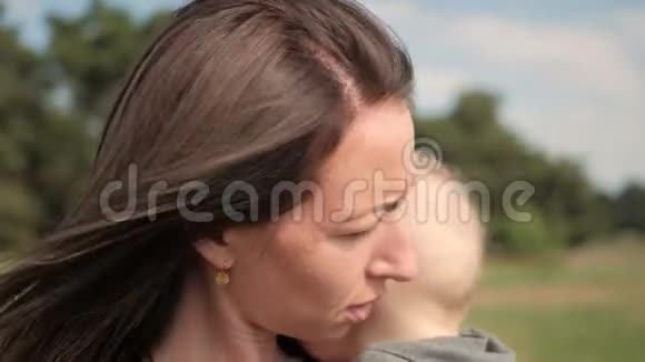 幸福的家庭在大自然户外母亲亲吻小男孩在绿色的草地上视频的预览图