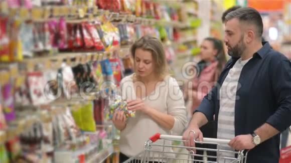 年轻夫妇在杂货店购物幸福的家庭有很多有趣的消费时间在一起找一些视频的预览图