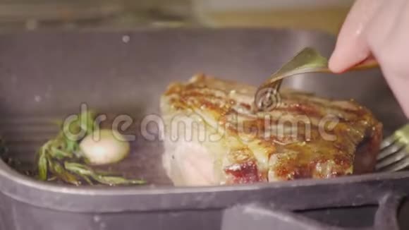 不可辨认的主厨他用两把叉子叉着一块多汁的牛排用迷迭香和大蒜烤视频的预览图