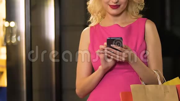 带着手机和滚动屏幕的购物袋的女孩在线折扣视频的预览图