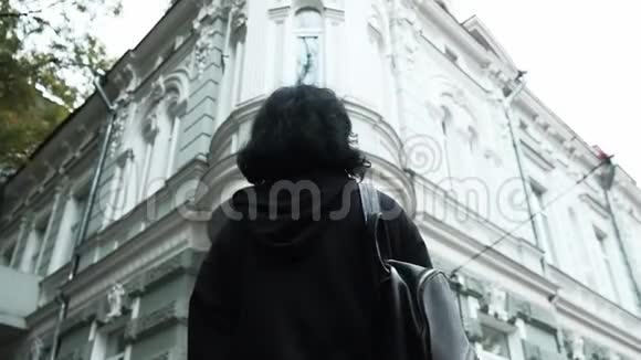 站在一条街中间的哥特式深褐色头发的女孩向后看视频的预览图