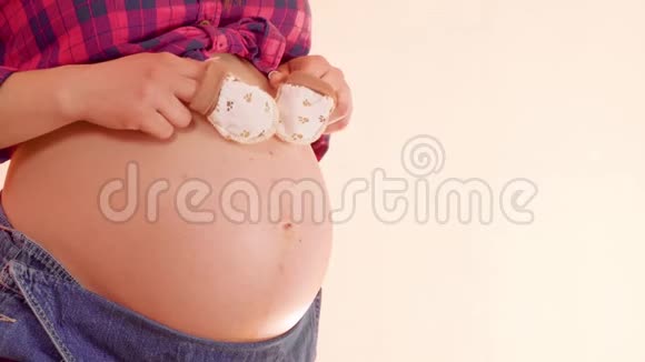 一个怀孕的女人在她赤裸的大肚子上戴着可爱的小手套走路想让妈妈玩视频的预览图