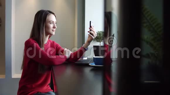 一个漂亮的女孩在咖啡馆做一个自拍视频的预览图