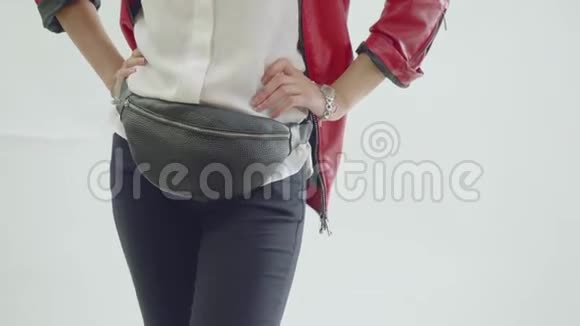 在拍照期间穿着棕色裤子和红色外套的女孩在臀部摆着范尼包视频的预览图