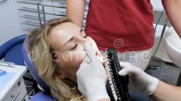 牙科医生在美白前检查病人牙齿颜色4k录像视频的预览图