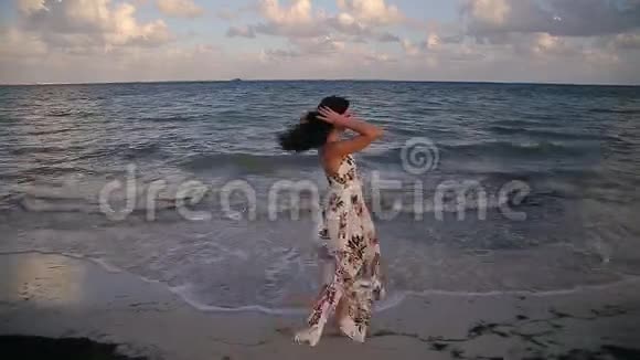 日落时分一位年轻的黑发女人在墨西哥坎昆附近的热带海滩上散步跑步和玩耍视频的预览图