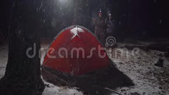 一对夫妇在一个下雪的夜晚在露营时互相交谈视频的预览图