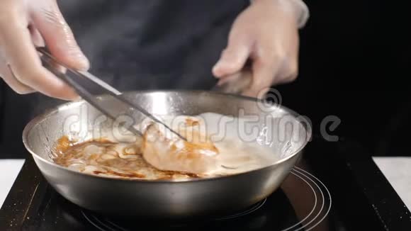 厨师烹饪手套的厨师准备海鲜在煎锅里用奶油酱煮扇贝高清高清视频的预览图