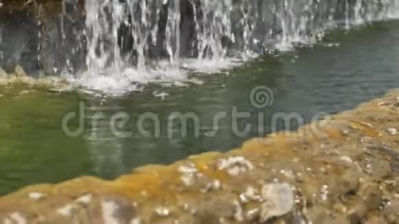 花园的石头瀑布水流过石头清晨的阳光照在瀑布上视频的预览图
