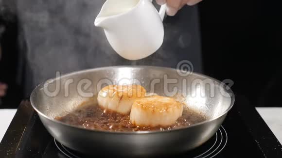 在餐馆做饭厨师在煎锅上倒入奶油用扇贝缓慢移动准备食物高清高清视频的预览图