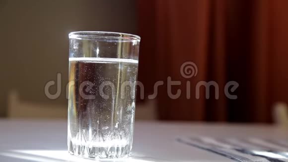 男人把泡腾的药片扔进桌子边的一杯水里视频的预览图