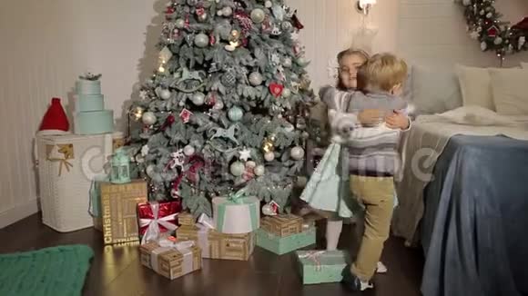 两个小孩抱在圣诞树旁视频的预览图