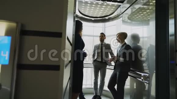 跟踪女商人和商人同事在电梯里交谈的镜头并准备在现代移动视频的预览图