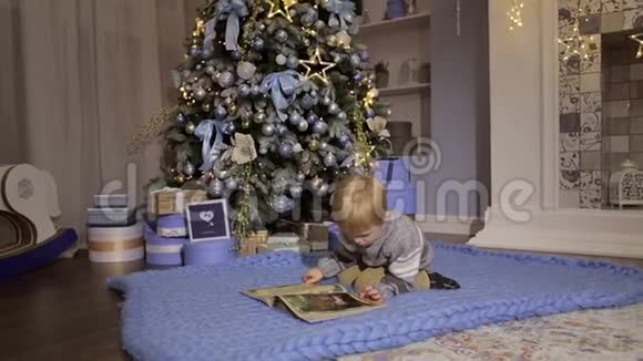 男孩躺在圣诞树附近的地板上拿着书视频的预览图